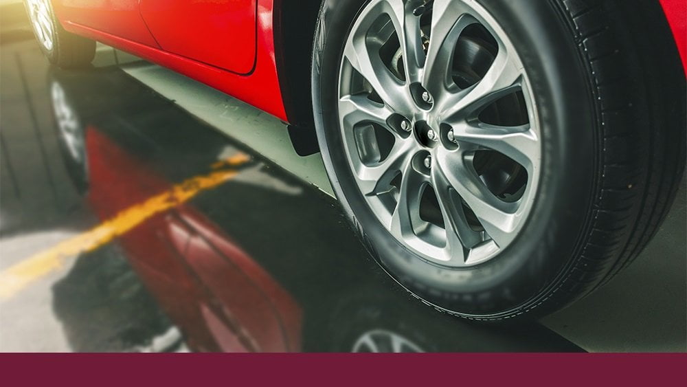 Imagem de um pneu de um carro vermelho, ilustrando o artigo "Quando trocar os pneus do carro?"