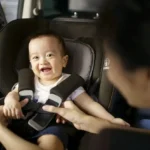 Bebê sorrindo em uma cadeira de segurança no carro com o sistema Isofix