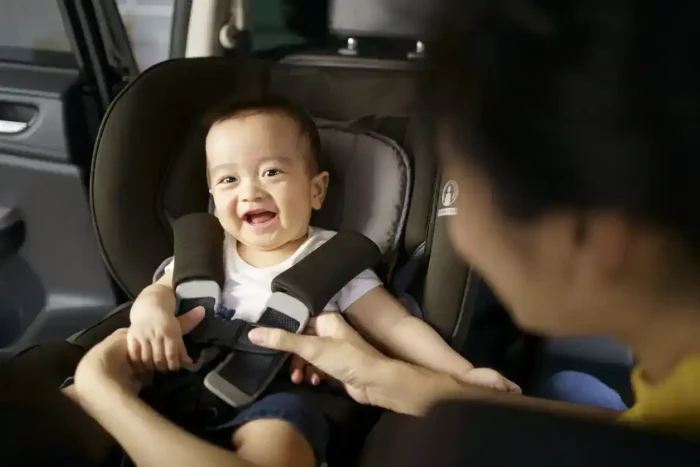 Bebê sorrindo em uma cadeira de segurança no carro com o sistema Isofix