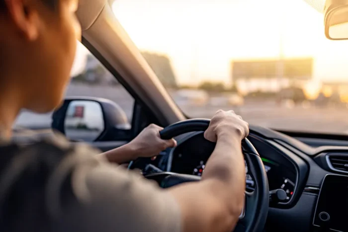 Condutor pratica direção defensiva ao volante em via urbana, atento ao trânsito e prevenindo acidentes.