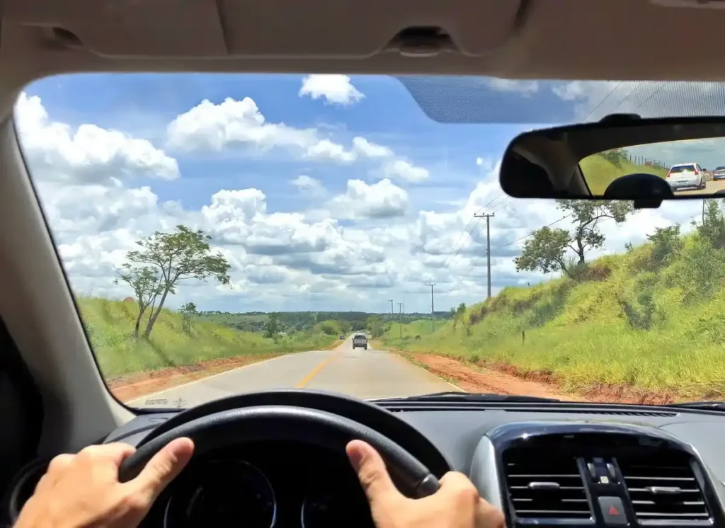 Motorista pratica direção defensiva em estrada rural, mantendo segurança e prevenindo colisões.