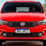 Carro vermelho Fiat com nova placa Mercosul padrão brasileiro, vista frontal em ambiente urbano