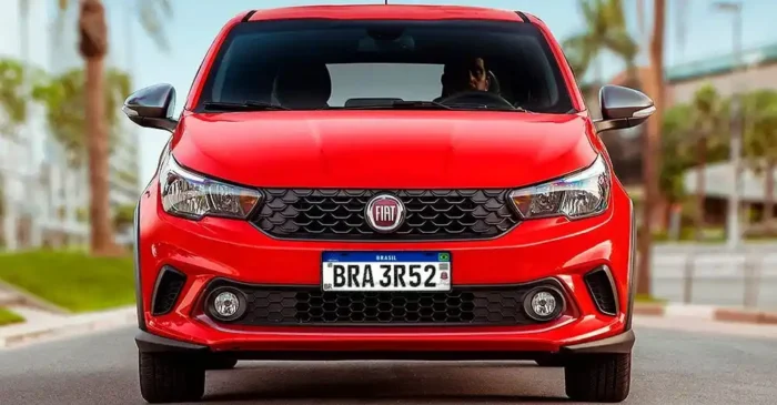 Carro vermelho Fiat com nova placa Mercosul padrão brasileiro, vista frontal em ambiente urbano