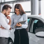 Cliente consultando tabela FIPE com vendedora de carros em concessionária
