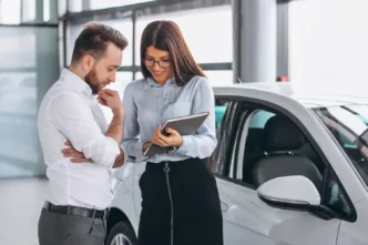 Cliente consultando tabela FIPE com vendedora de carros em concessionária