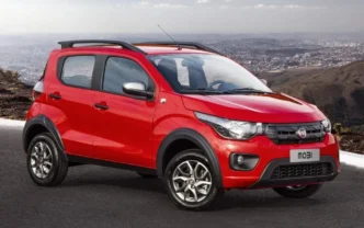 Fiat Mobi vermelho, carro pequeno da Fiat, estacionado em estrada com vista panorâmica ao fundo.