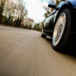 Carro em alta velocidade visto de baixo, com efeito de movimento na pista; contexto de multa por excesso de velocidade.