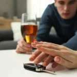 Pessoa impede motorista com bebida alcoólica de pegar a chave do carro, simbolizando multa por embriaguez ao volante.