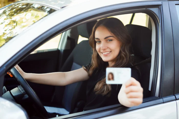 Mulher segurando CNH dentro do carro, representando alternativas para obter CNH sem autoescola.