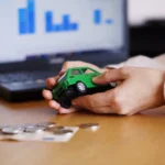 Pessoa segurando um carro em miniatura ao lado de dinheiro e notebook, representando o pagamento do IPVA 2026 em Minas Gerais.