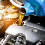 Troca de óleo do motor sendo realizada com lubrificante sendo despejado no carro