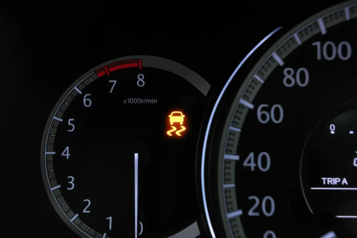 Painel de instrumentos de um carro com a luz de controle de estabilidade acesa em amarelo, ao lado do conta-giros na faixa vermelha.